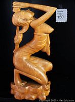 Right side view of the wooden sculpture showing details of woman's pose and carved base
