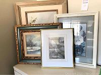Five framed artworks arranged together showing nature and floral themes, various frame styles and sizes
