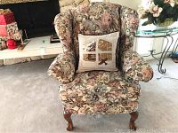 Front view of floral wingback armchair with pillow.