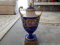 Front view of blue German urn with gold handles and base, showing overall shape and decoration.
