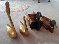 Side view of two gold metal geese and two wooden ducks arranged on carpet.