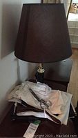 Lamp with brown textured lampshade and metal base, fabric pieces in front, metal sewing scissors on fabric