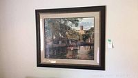 Framed garden scene painting showing water, trees, and architecture in soft natural colors.