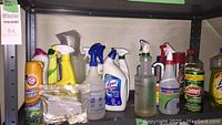 Shelf with various cleaning supplies including sprays, powders, and bottles