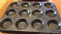 Photo of a 12-cup metal muffin pan with some wear visible on the surface.