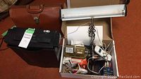 Overview of the lot showing leather bag, shredder, desk clock, and various stationery items in a box