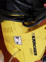 Close-up of the yellow Karcher 360 carpet cleaner nameplate and power cord.