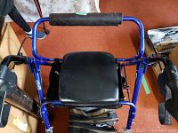 Photo of blue metal walker with padded black seat and storage pouch below seat, showing condition and structure