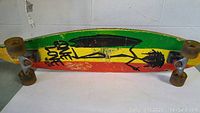Side view of skateboard showing colorful graphic with 'One Love' text and stylized character on the bottom of deck.