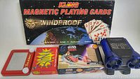 Photo of Kling Magnetic Playing Cards box, red Etch A Sketch, Star Wars Swoop vehicle box, Blink card game box, and Creative Playworks binoculars showing overall contents and condition.