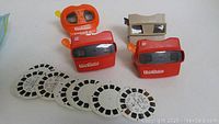 Four View-Masters viewers along with seven View-Master slide reels arranged on a flat surface.