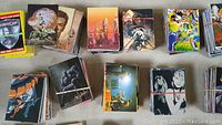 Overview of multiple bundles of trading cards laid out on a surface, showing art from RoboCop, superheroes and other themes.