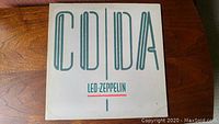 Front cover of Led Zeppelin vinyl album 'Coda' with white background and large teal letters, band name in red underneath.