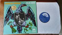 Front cover of Charles Mingus Blue Bird vinyl record showing detailed artwork and the record partially inside the sleeve.