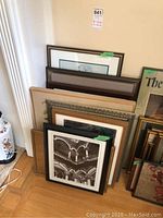 Overall view of framed artwork leaning against wall showing multiple pieces of different sizes and frames