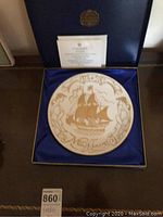 Decorative commemorative plate featuring the Mayflower ship in gold on white bone china, displayed inside a blue silk-lined presentation box.