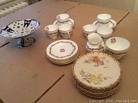 Top view of the tea set laid out on a table showing six tea cups, six saucers, six desert plates, cream jug, sugar bowl, and a large blue and white pierced dessert tray on a pedestal