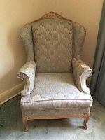 Front view of the wing back chair showing the upholstery, carved wood top rail and cabriole legs.