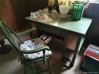 Green desk and chair set shown together with visible floral cushioned chair seat and carved desk legs.