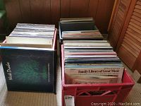 Three red plastic bins filled with assorted vinyl records including Nick Drake, Eagles, and orchestral collections.