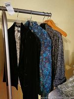 Three ladies jackets on hangers including black velvet, blue knit, and black and white herringbone pattern.