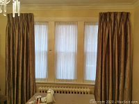 Silk bronze drapes and sheer curtains covering three windows, pleated drapes on each side with sheers in the middle panels.