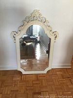 Full view of the carved painted mirror showing its size and ornate frame with a carved crest detail at the top.