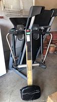 Treadmill folded up with rowing machine frame visible