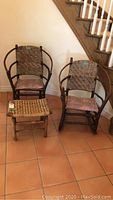Front view of Old Hickory matching chair and rocking chair with footstool in front on tile floor.