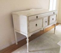Side view of the wooden painted sideboard showing legs, drawer, and cupboard doors