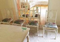 Set of six white painted vintage wooden dining chairs with floral fabric upholstered seats, five standard size and one larger captain chair