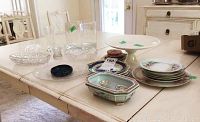 Wide view of glass bowls, plates, and cake stand on table showing overall assortment and condition.