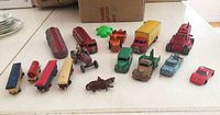 Overview of 9 die cast vehicles, wooden train carriages, and the Mountie on horse figurine arranged on a table.