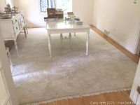 Full view of cream wool rug under dining table showing overall layout and fringe at far end
