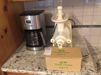 Cuisinart coffee maker and Green Power juice extractor with parts box on countertop.