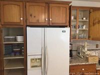 Photo of two cupboards in kitchen including shelves with plates, mugs, glasses, food storage containers, grater, and other kitchen items