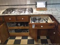 Kitchen cabinets open revealing a set of stainless steel pots and some cast iron pans