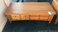 Full view of rectangular pine coffee table with four drawers and wooden knobs, light wear on surface visible.