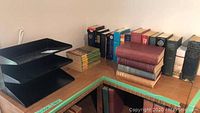 Wide shot showing the collection of vintage and newer books on a wooden desk including a black metal tiered organizer.