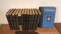 Front view of 11 black hardcover Stoddard's Lectures with one blue hardcover book titled 'Canada - Foundations of Its Future' by Stephen Leacock