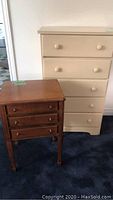 Photo of the beige dresser and brown end table side by side on carpet, showing overall shape, color, and wear.