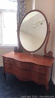 Front view of full vintage wooden dresser with oval mirror attached on top
