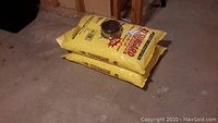 Two unopened yellow bags of Resingard Salt Pellets stacked on floor.
