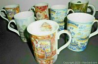 Group photo showing all 7 collectible mugs with varied colorful artistic patterns, cottage scenes, and classic blue and white tea imagery.