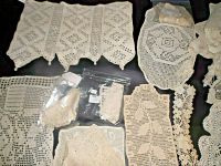 Top-down photo showing delicate and patterned filet crochet pieces, including rectangular and oval shapes, with fine crochet mesh and lace motifs, some in plastic bags.
