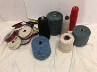 View of 10 ribbon spools and 7 large yarn spools arranged on a white background.