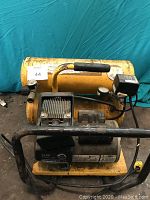 Front view of yellow portable air compressor on black frame