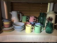 Overall view of the set including Fiestaware mugs, bowls, saucers, Ball jars, and Lenox coffee container