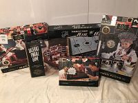 Photo showing all the boxed games together: FAO Schwarz Wooden Kitchen, Brown box of Wembley Baseball Pinball Game, NHL Tabletop Air Hockey box, FAO Schwarz Magic Set, and FAO Schwarz Marble Stunt Run box.