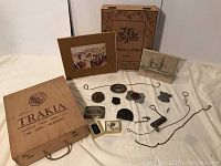Photo showing the two large wooden wine boxes, the five large belt buckles, necklaces, keychain, pin, and the two art prints laid out on a flat surface.
